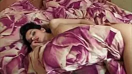 A busty brunette beauty, Katie Fey, rolls naked in bed, teasing with her bare breasts.