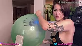 cute brunette teen inflates big green balloon at home