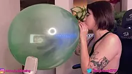 cute brunette teen inflates big green balloon at home
