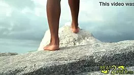 Teen brunette giggles as her feet get wet at the beach on beat2feetcom.