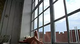 The beautiful babe poses erotically, undressing by the window in this behind-the-scenes video