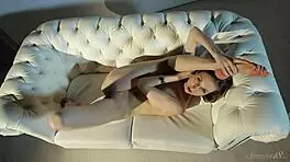 gorgeous teen 18+ model touches her body on a white sofa.