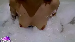 Feeling horny, cute babe sloppily sucks huge dildo in foamy bath close-up