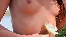Naked redhead teen plays with water lily