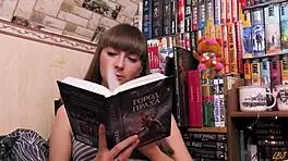 student reads book and sensually fingers her pussy alone at home