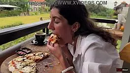 Enjoying a mouthful of pizza on the street in a public cafe with beautiful teen