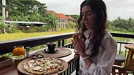 Enjoying a mouthful of pizza on the street in a public cafe with beautiful teen