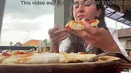 Enjoying a mouthful of pizza on the street in a public cafe with beautiful teen