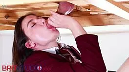 Feeling naughty, uniformed brunette Ellie passionately milks cock at milking table.