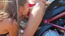 brunette teen passionately licks and kisses during outdoor bike wash