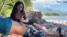 Skinny brunette strokes huge cock to cum on public beach
